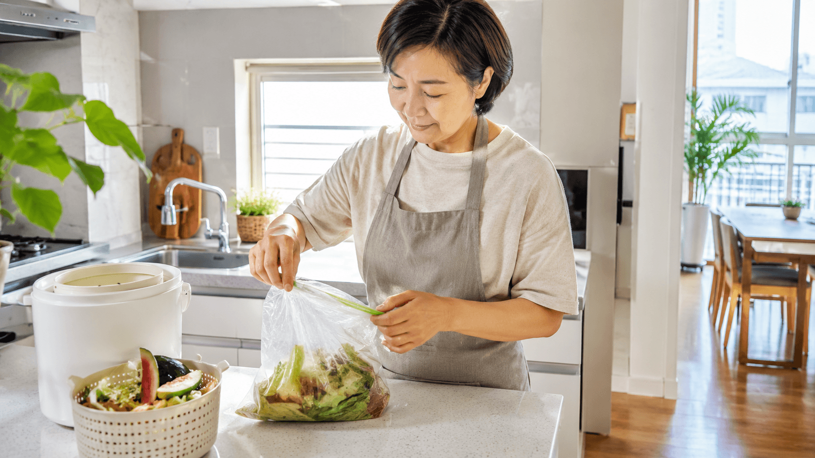 음식물쓰레기 냄새 줄이는 법을 설명하는 여름철 주방에서 50대 한국인 여성이 음식물쓰레기의 물기를 빼고 밀폐해 정리하는 위생적인 장면